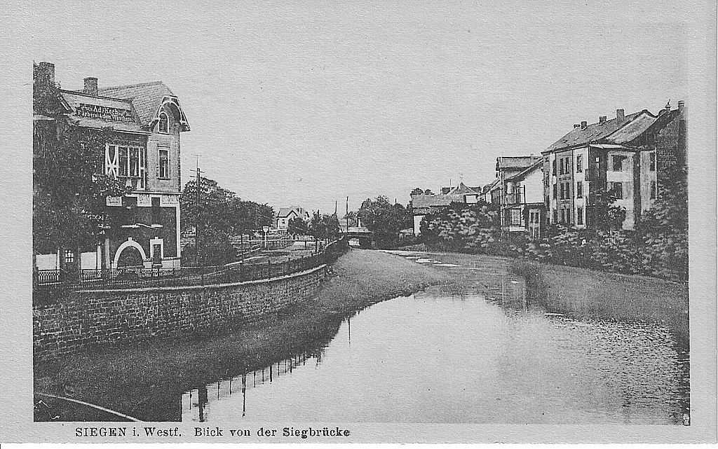 “Blick von der Siegbrücke“. Historische Ansichtskarte (datiert um 1910) mit Blick auf die Wiesen des Siegufers, über die ab 1968 die “Siegplatte“ errichtet werden sollte. Am linken Bildrand die Färberei Adolf Koch (Quelle: Stadtarchiv Siegen, Best. Ansichtskartensammlung) 