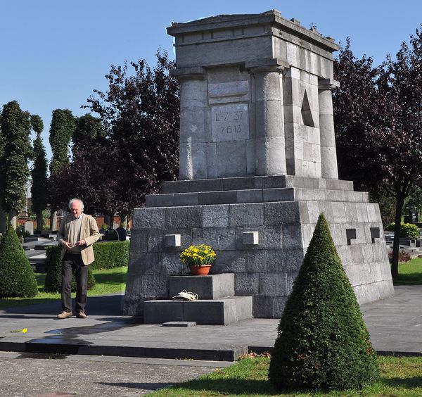 LZ 37-Denkmal auf dem Genter Westfriedhof. Hinter der Grab-Bodenplatte von Obltn. Otto van der Haegen (Inschrift eingraviert auf der Bodenplatte) steht der Enkel des ehemaligen  LZ 37-Maschinisten Carl Clauss, dessen Grab damals 1956 mit allen anderen deutschen Soldatengräbern aus WW I und WW II auf den deutschen Soldatenfriedhof in Vladslo umgebettet wurde.  Enkel Gert-Rücker (74) besuchte  gemeinsam mit  Autor Günter Dick aus Sankt Augustin im September 2010 das Erinnerungsdenkmal. Hierbei wurde auch die Idee für eine dort notwendige Informations-Tafel angeregt. Die Grabplatte von Kurt Ackermann-Berlin liegt verdeckt hinter dem Spitz-Buchsbaum. Foto: © Günter Dick  